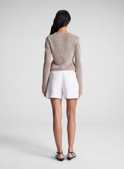 woman wearing tan sweater and white shorts