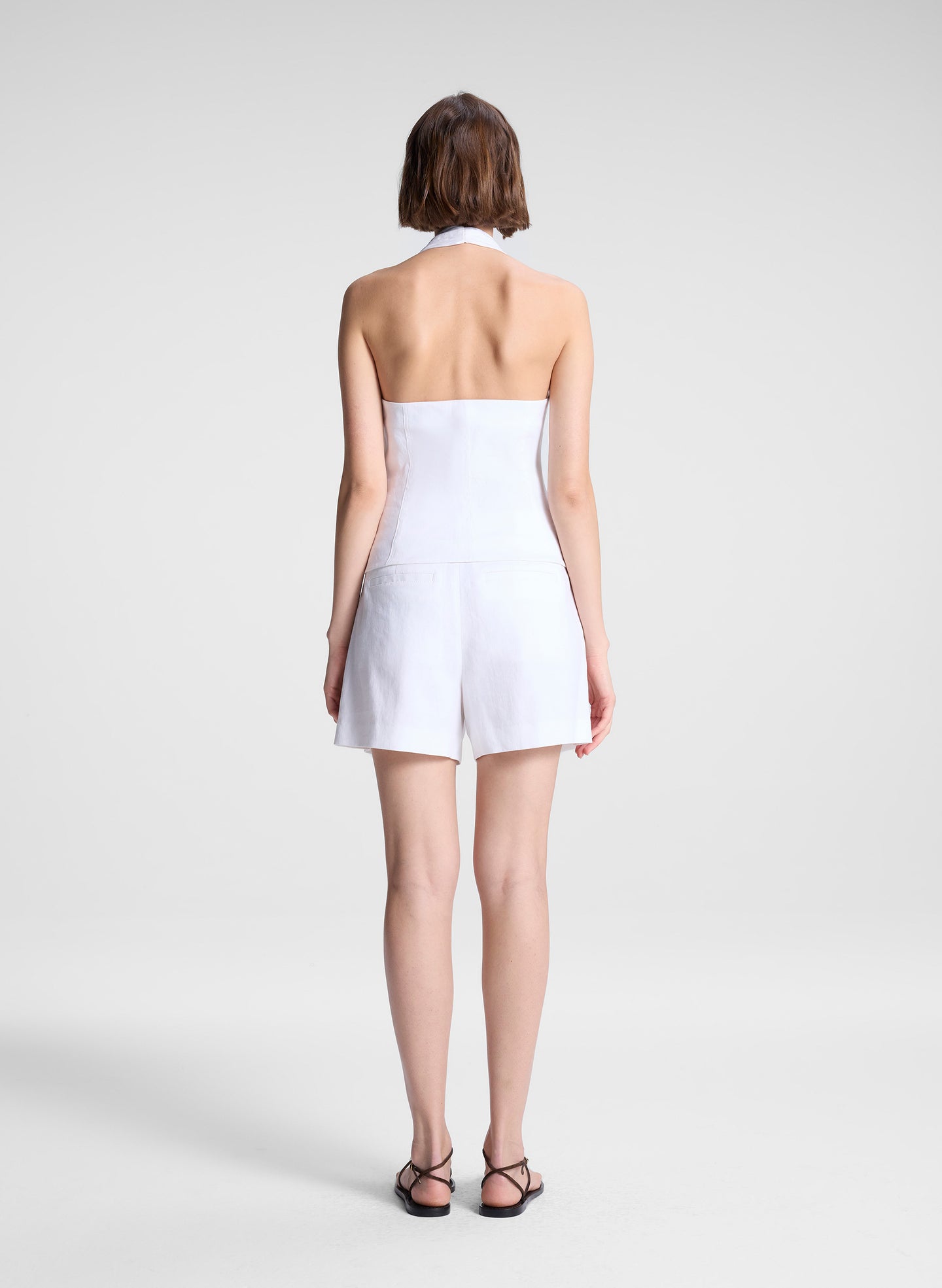 woman wearing white halter top and white linen shorts