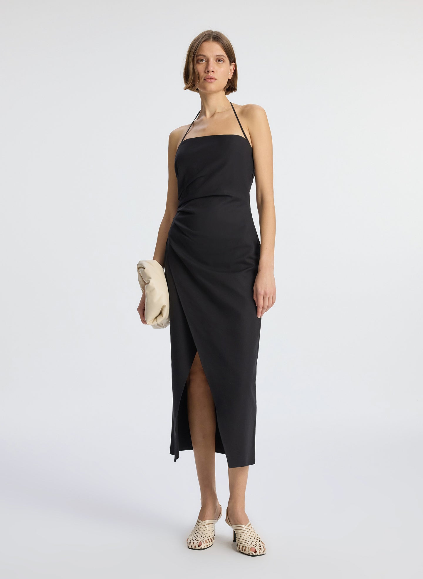 front view of woman wearing black halter neckline ruched midi dress