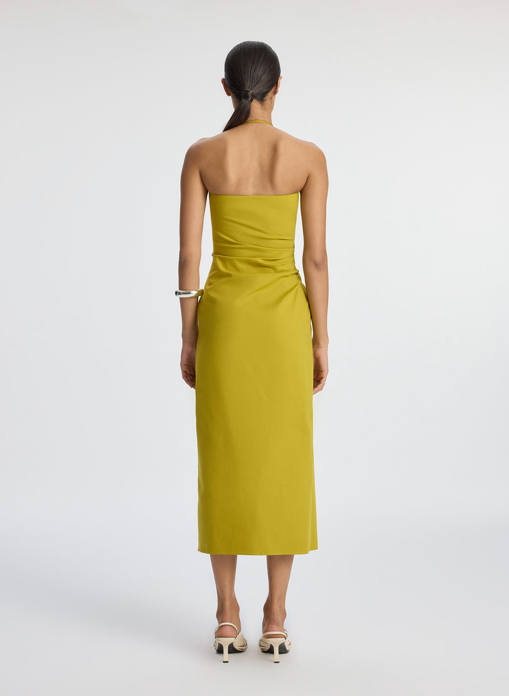 back  view of woman wearing yellow halter neckline ruched midi dress