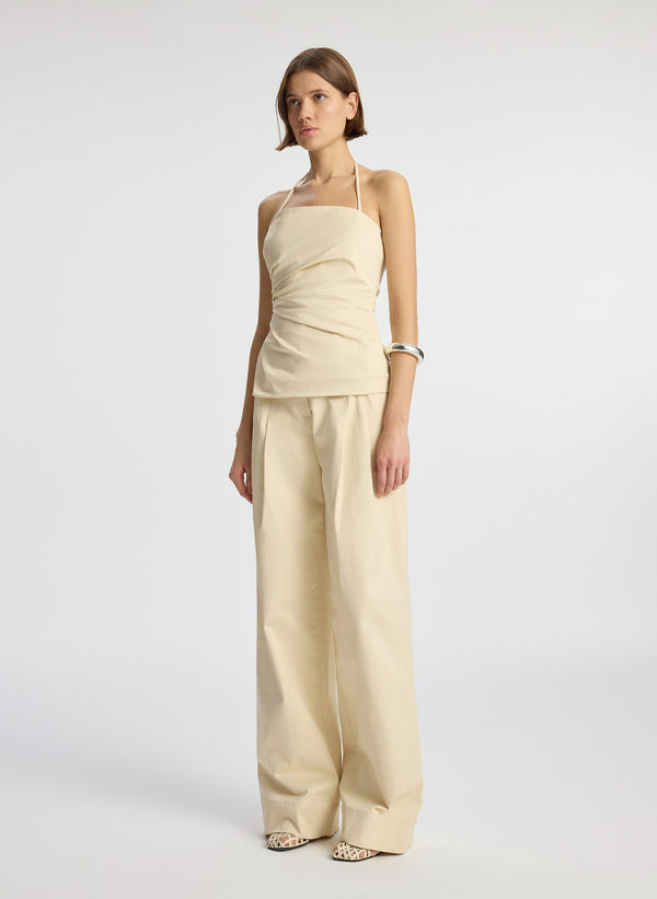side view of woman wearing beige sateen halter top and matching sateen wide leg pants
