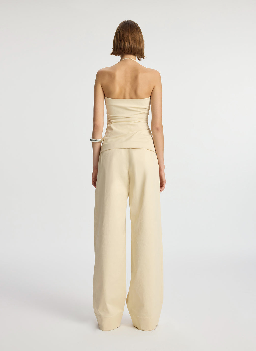 back  view of woman wearing beige halter top with side ruching and beige wide leg pant