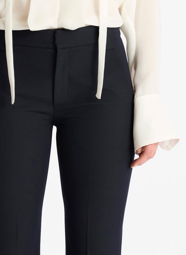 detail view of woman wearing white long sleeve blouse and navy blue flared pants