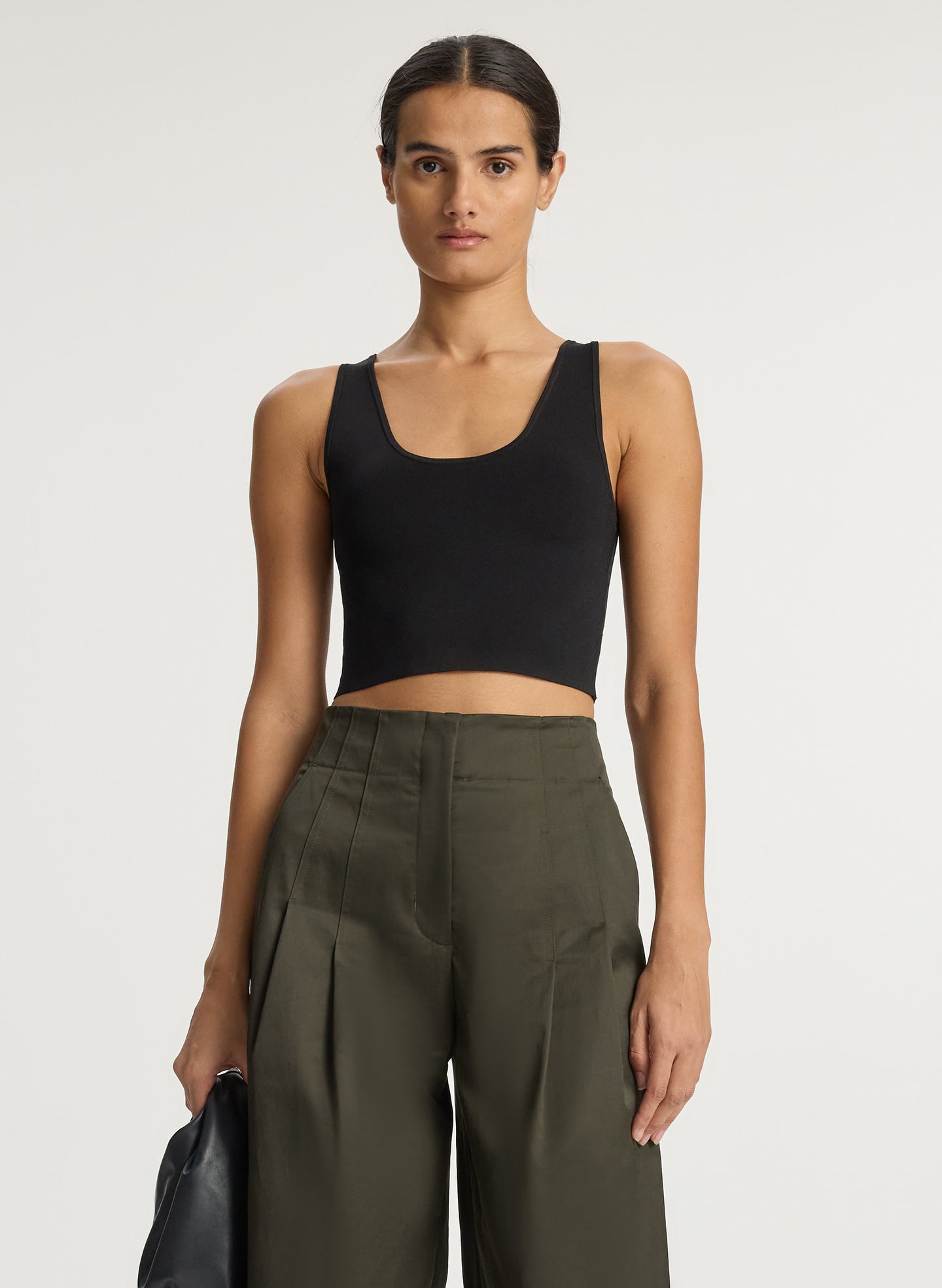front view of woman wearing black compact knit tank top and olive green pants
