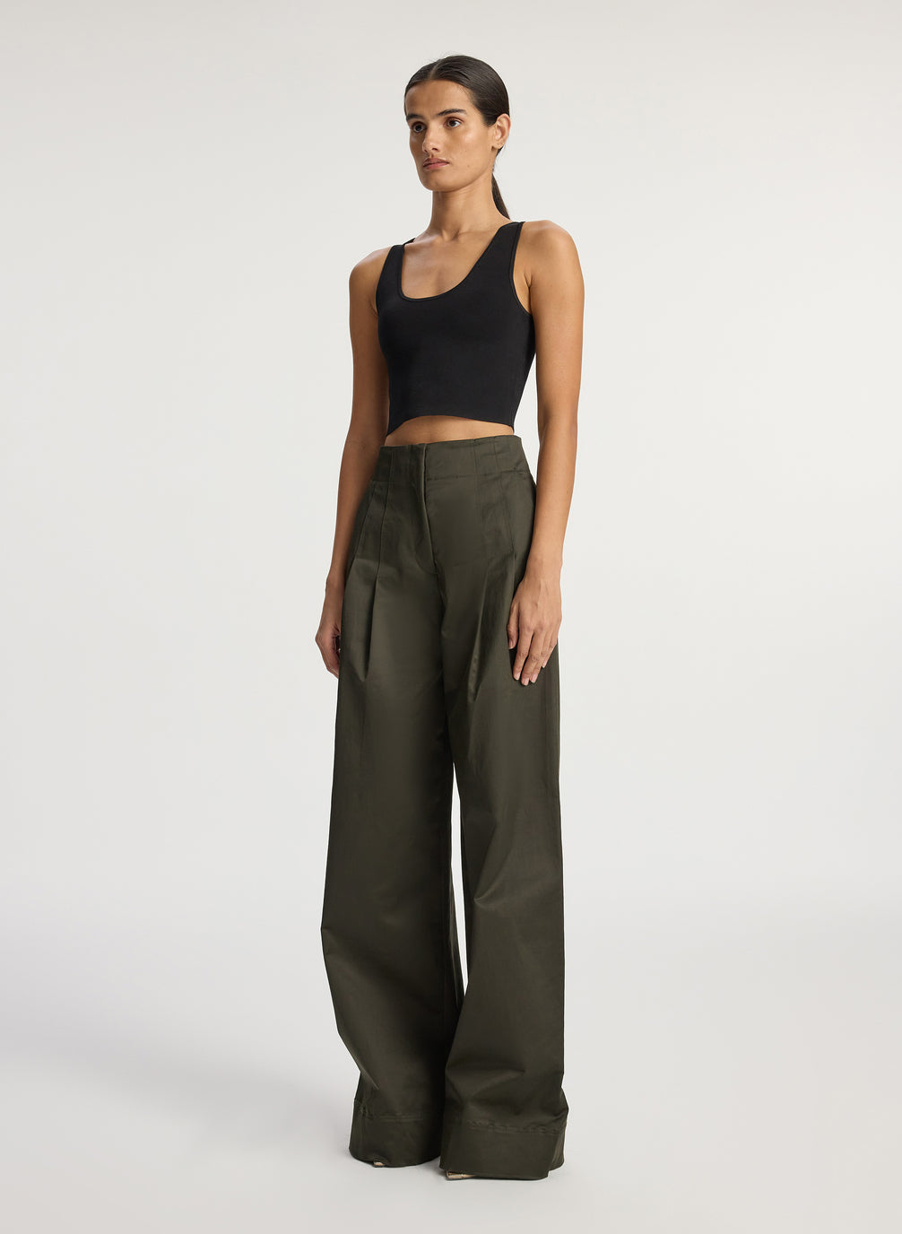 side view of woman wearing black compact knit tank top and olive green pants