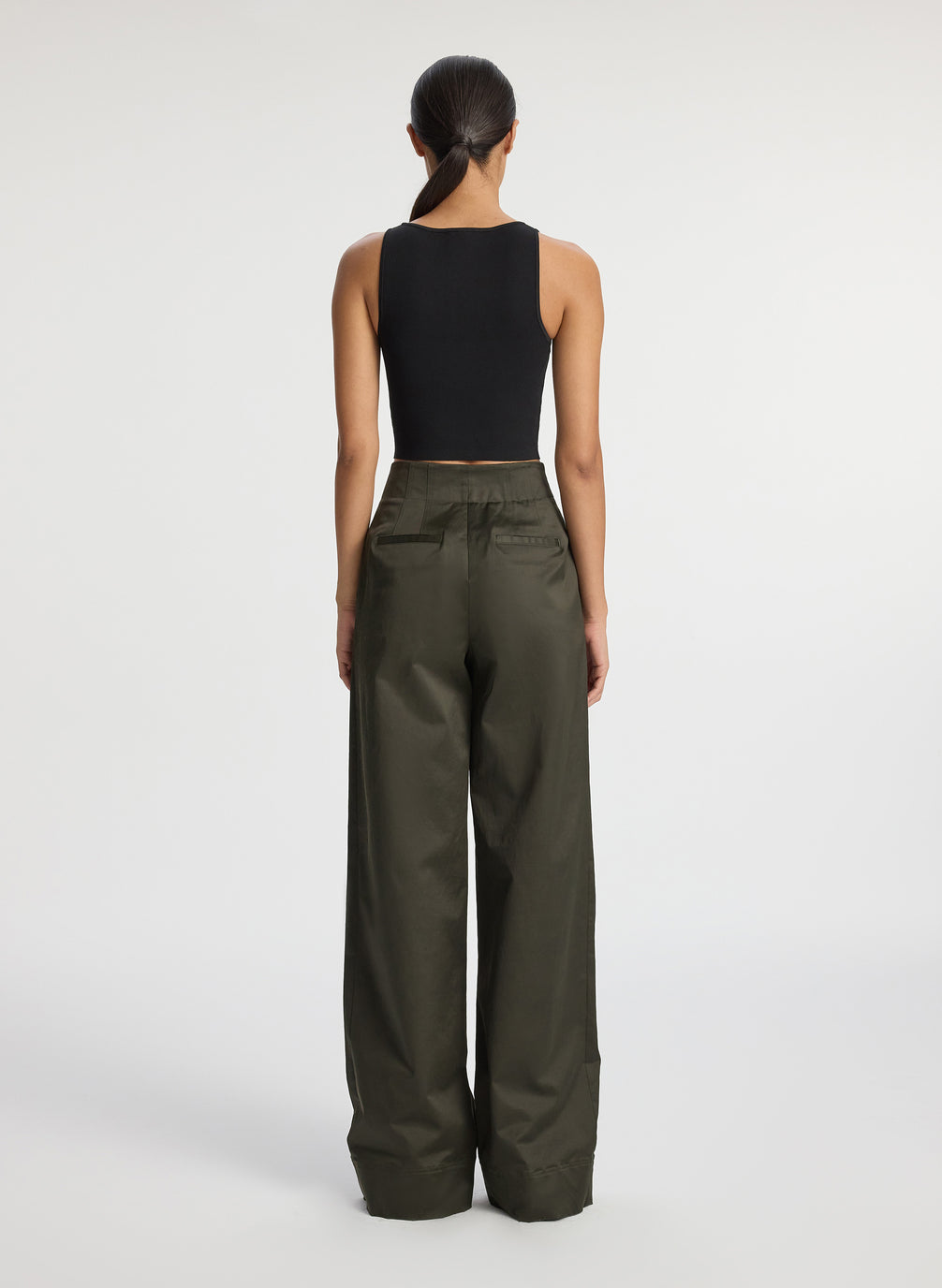 back view of woman wearing black compact knit tank top and olive green pants
