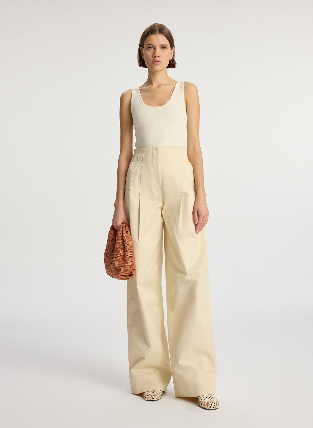 front view of woman wearing beige compact knit tank top and beige sateen wide leg pants