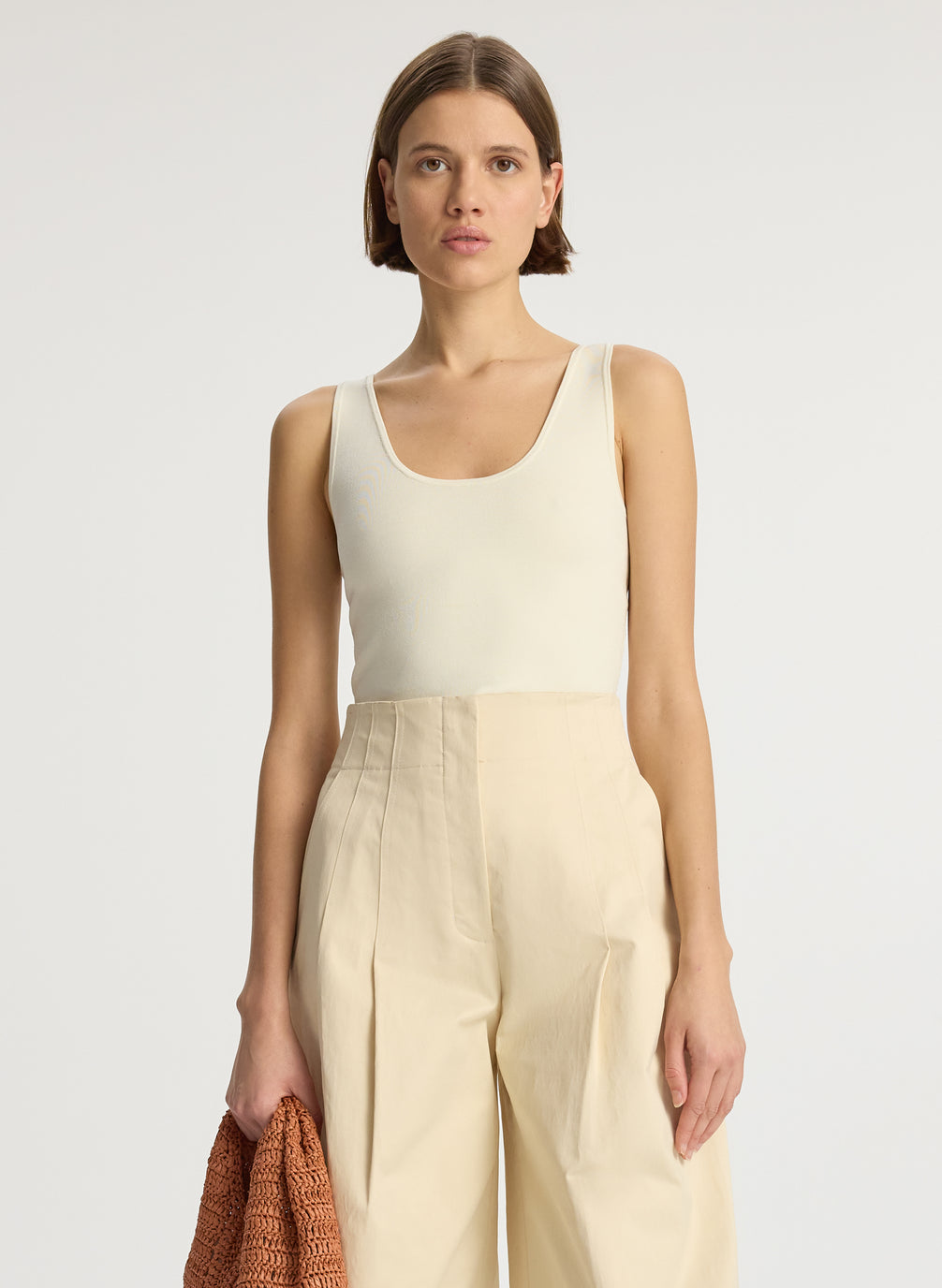front view of woman wearing beige compact knit tank top and beige sateen wide leg pants