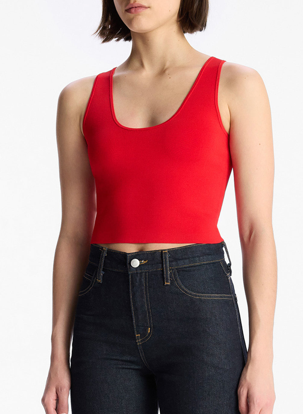 detail view of woman wearing red sleeveless top and dark wash denim jeans