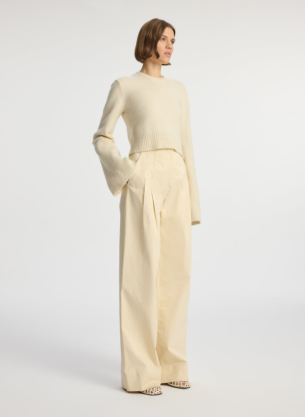 side view of woman wearing cream sweater and beige pants