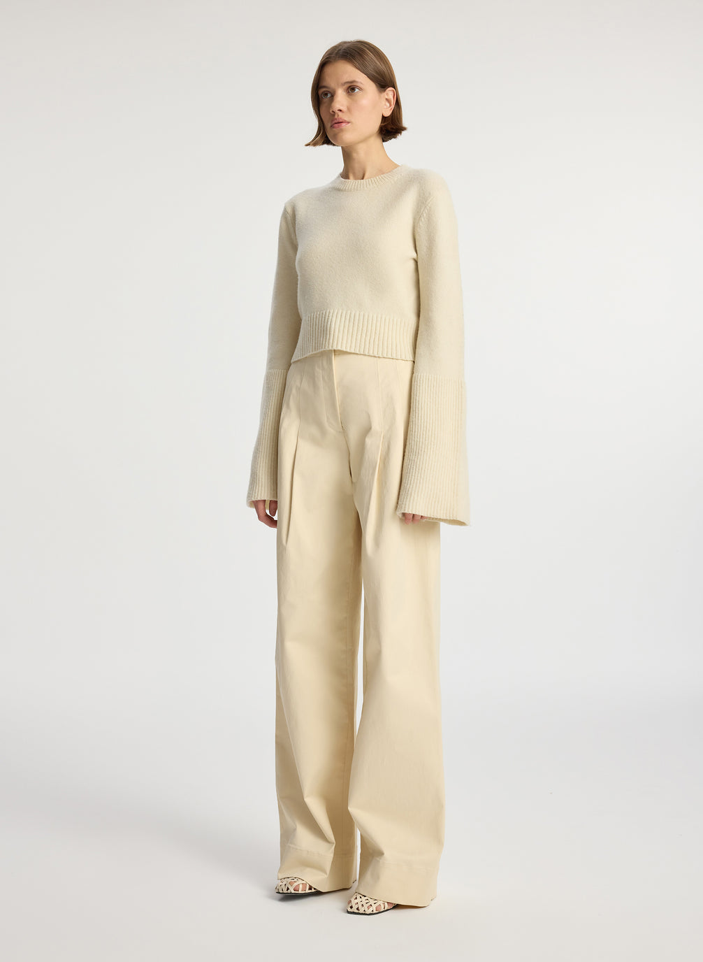 side view of woman wearing cream sweater and beige pants
