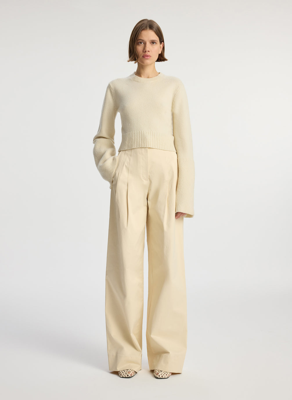 front view of woman wearing cream sweater and beige pants