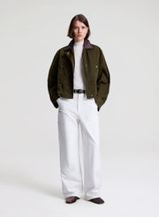 woman wearing green jacket and white top and pants