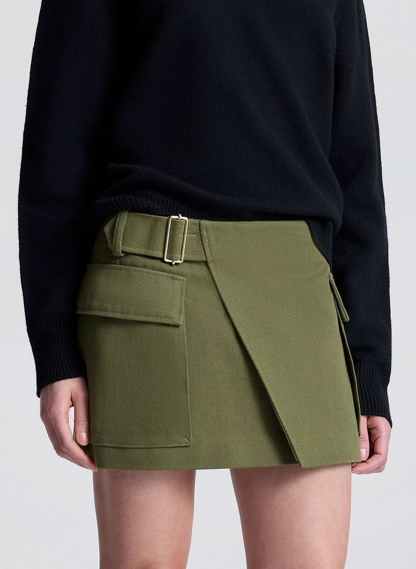woman wearing black v neck sweater and olive green wrap mini skirt