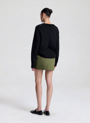 woman wearing black v neck sweater and olive green wrap mini skirt