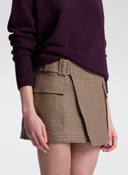 Person wearing a plaid skirt and dark sweater on a white background