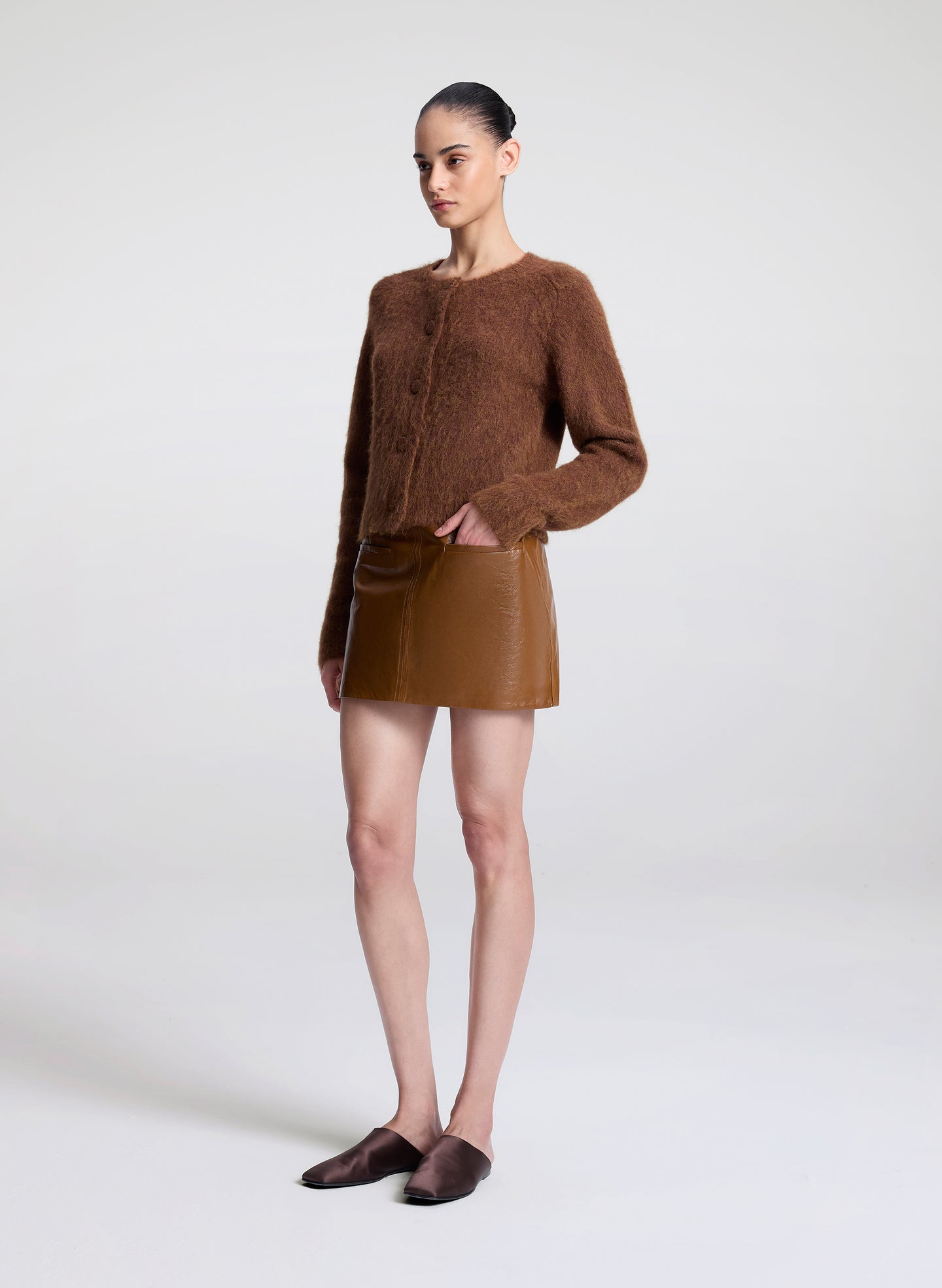 Woman wearing a brown sweater and skirt on a white background