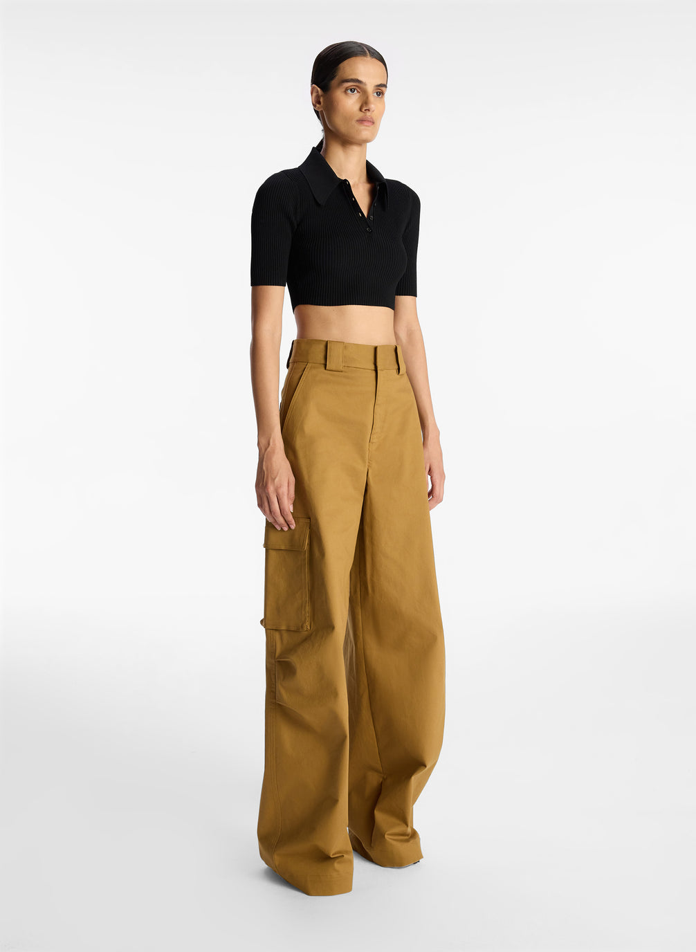 side view of woman wearing black cropped collared knit shirt and tan cargo pants