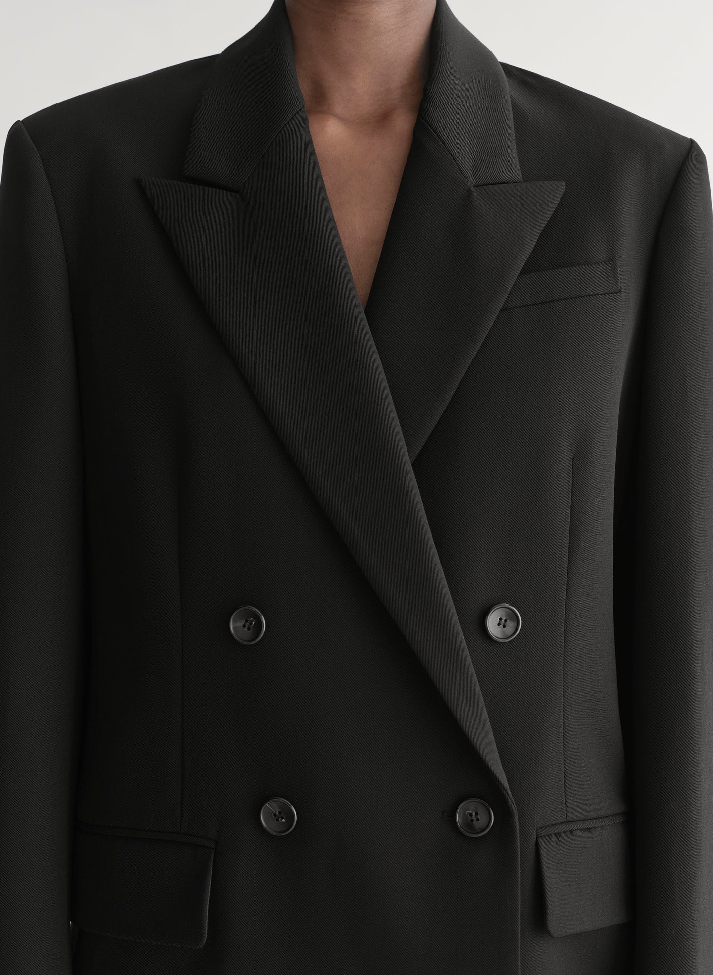 Close-up of a black double-breasted blazer with buttons on a neutral background