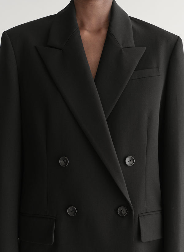 Close-up of a black double-breasted blazer with buttons on a neutral background