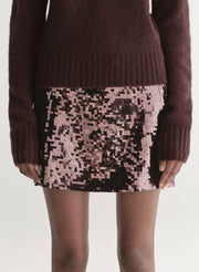Brown sweater and sequin skirt on a plain background