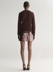 Person wearing a brown sweater and sequin skirt on a white background