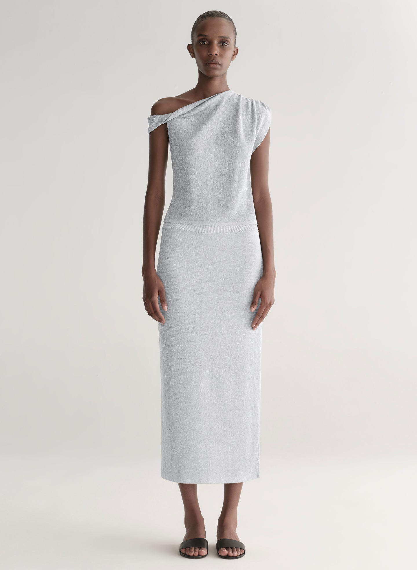 woman wearing silver one shoulder top and matching midi skirt