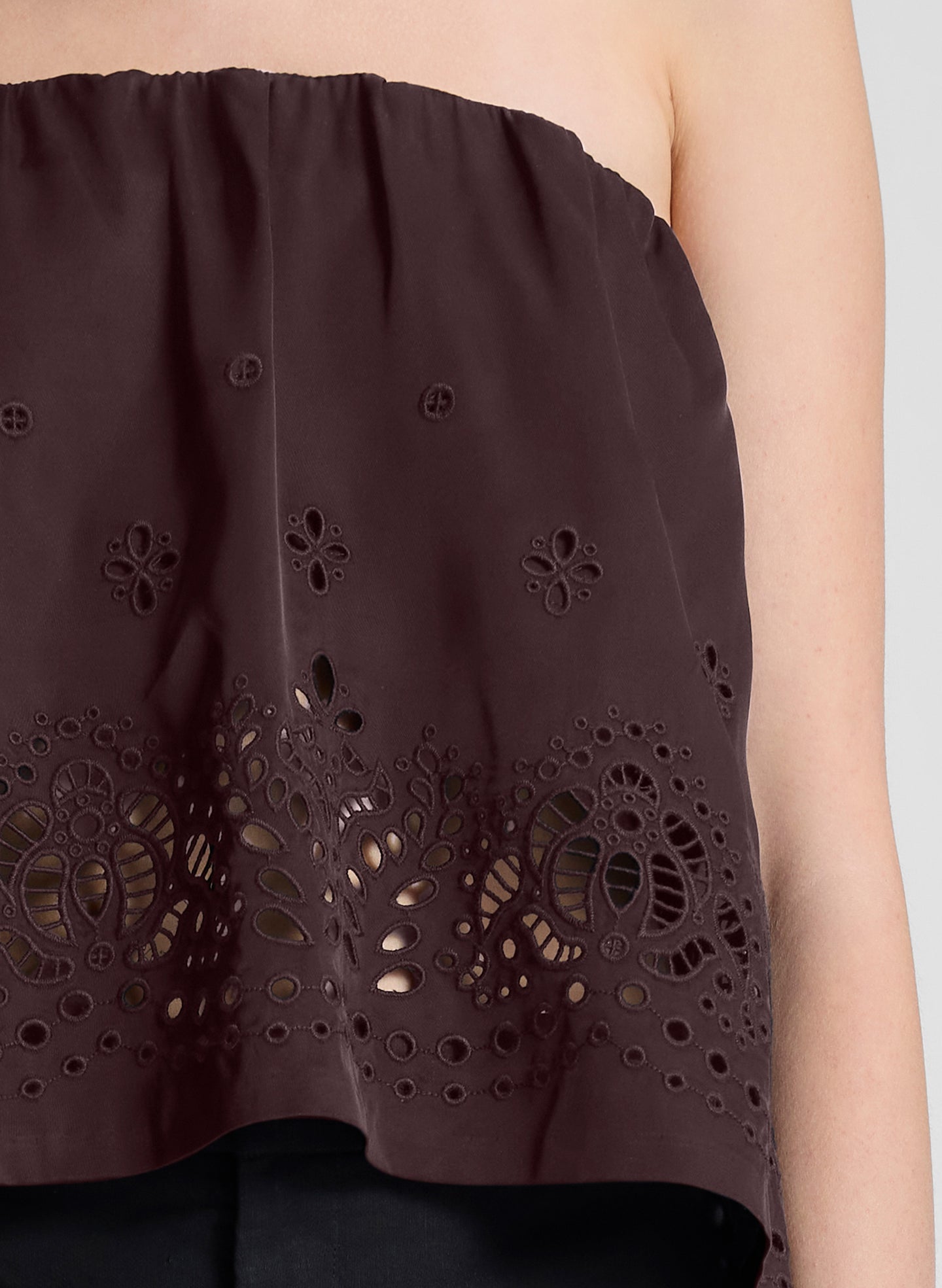 woman wearing dark brown strapless embroidered top with black capri pants