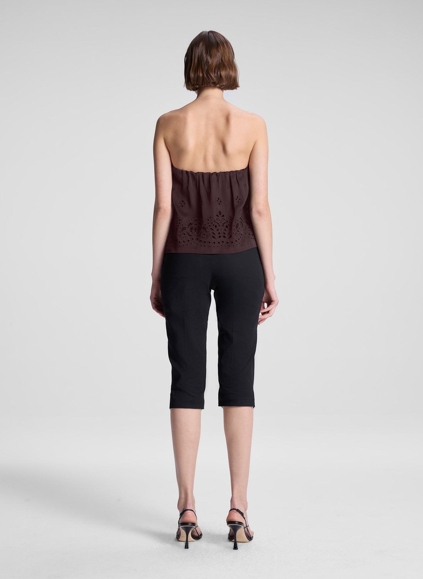woman wearing dark brown strapless embroidered top with black capri pants