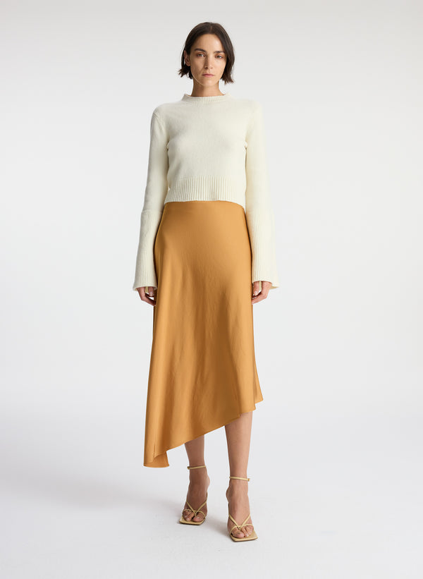 front view of woman wearing white sweater and brown satin asymmetric midi skirt 
