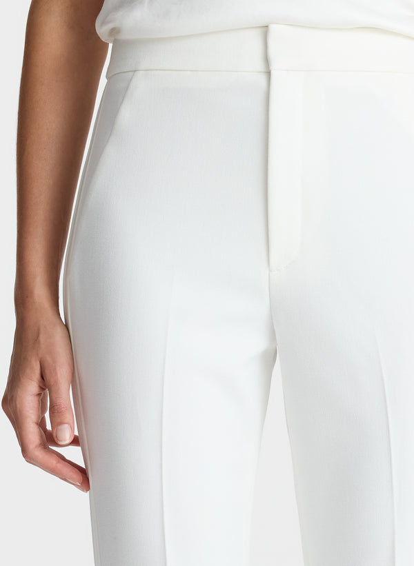 detail view of woman wearing white satin camisole and white flared tuxedo pants