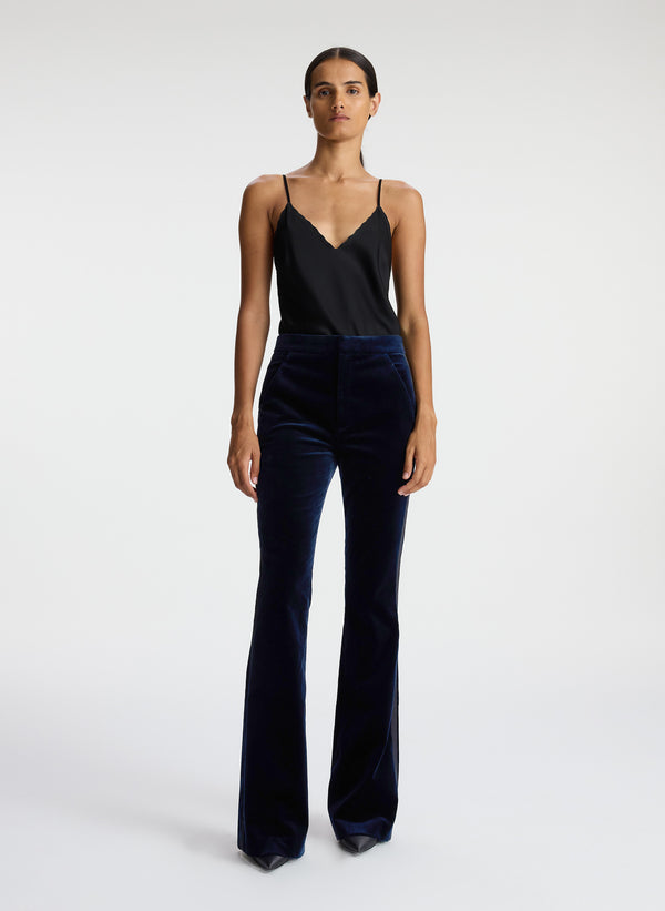 front view of woman wearing black satin camisole and navy blue velvet flared tuxedo pants