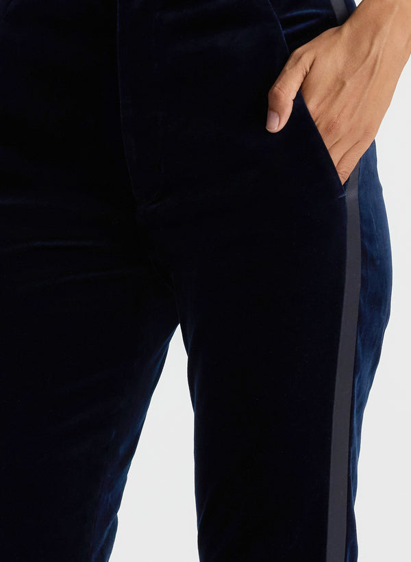 detail view of woman wearing black satin camisole and navy blue velvet flared tuxedo pants