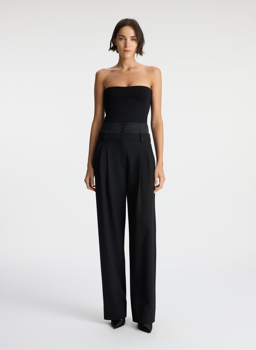 front view of woman wearing black strapless compact knit top and black satin pants