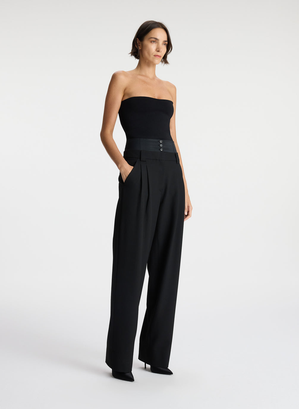 side view of woman wearing black strapless compact knit top and black satin pants