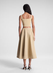 woman wearing beige zippered tank top and matching set beige midi skirt