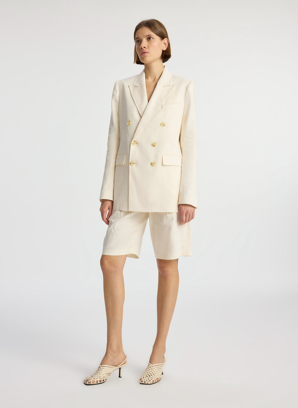 side view of woman wearing cream shorts suit
