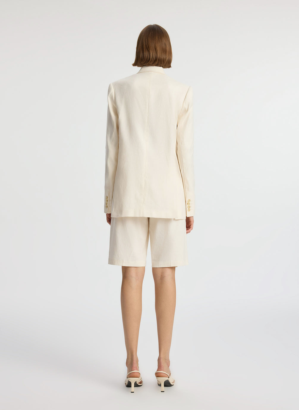 back view of woman wearing cream shorts suit