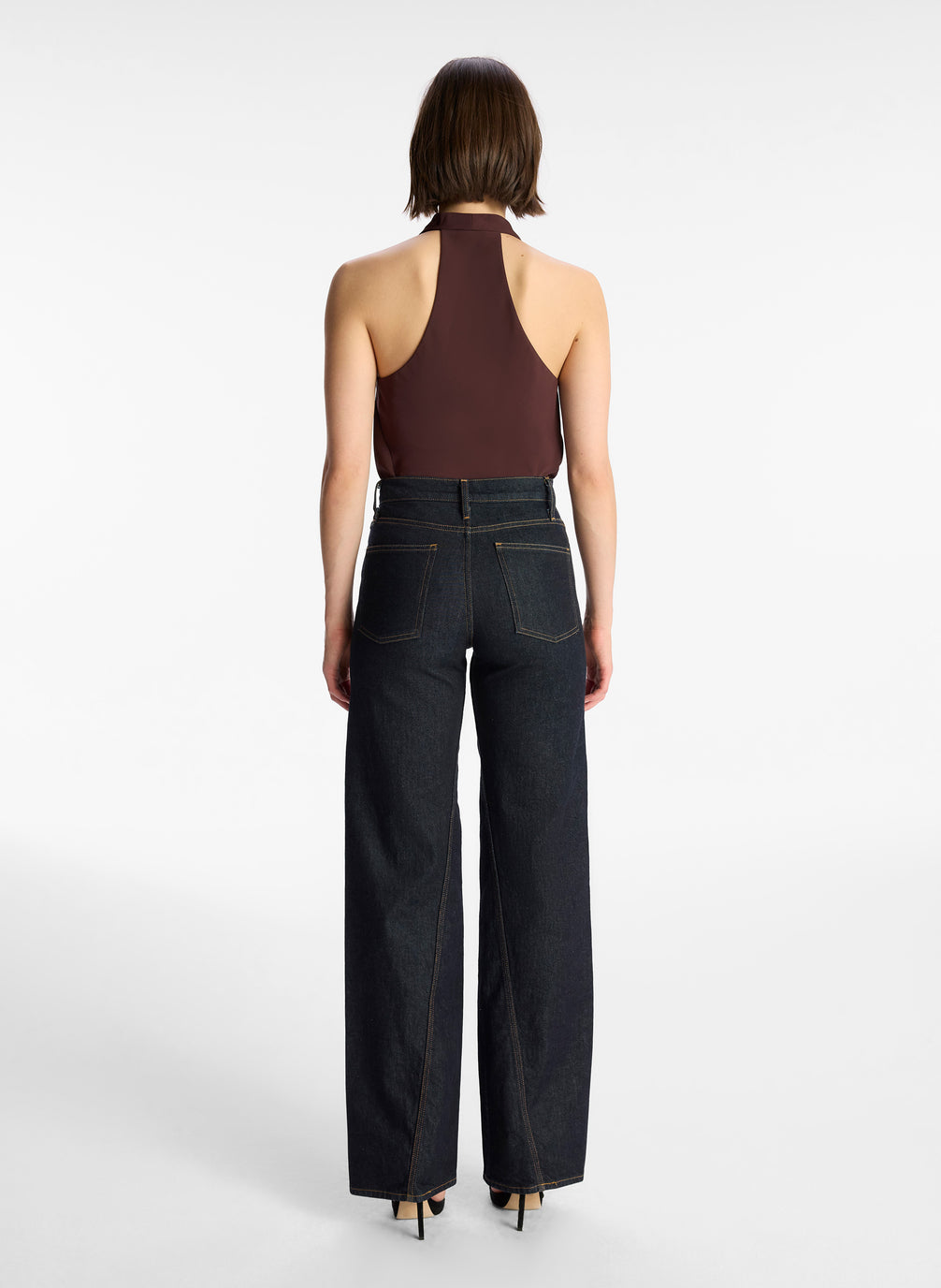 back view of woman wearing brown halter top and dark wash jeans