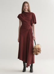 model in red dress carrying brown faux fur bag