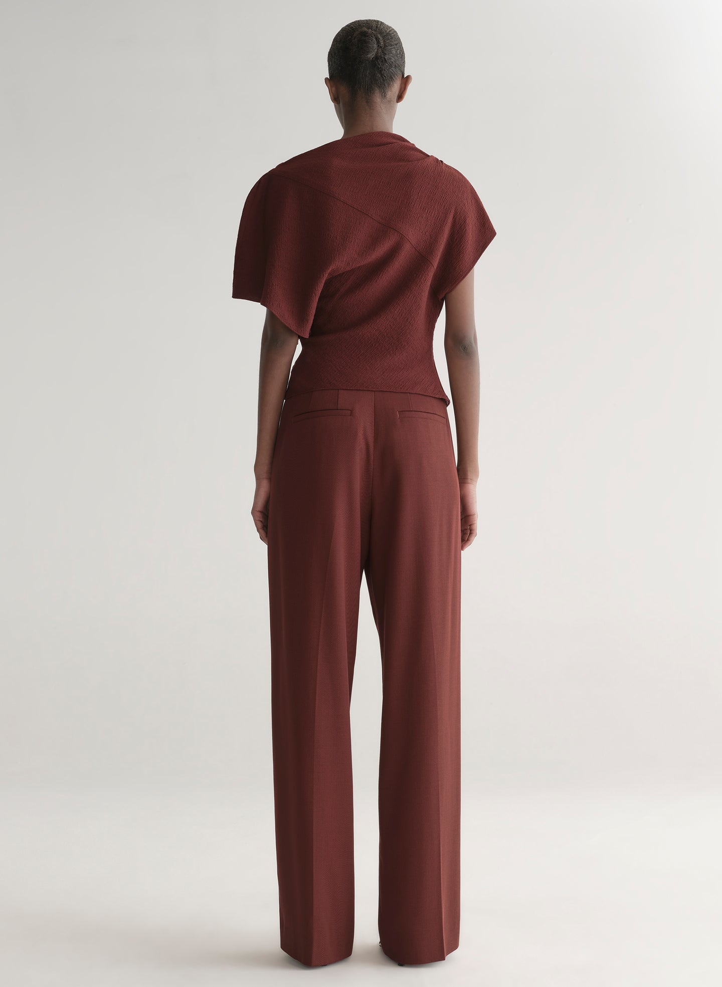 woman wearing maroon draped top with matching wide leg pants