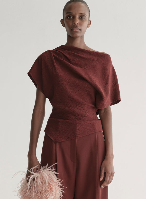 woman wearing maroon draped top with matching wide leg pants