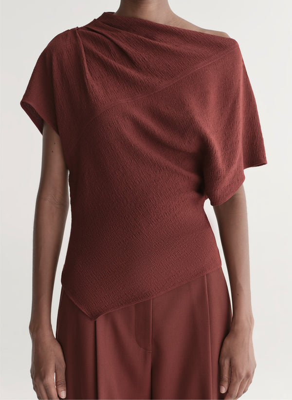 woman wearing maroon draped top with matching wide leg pants