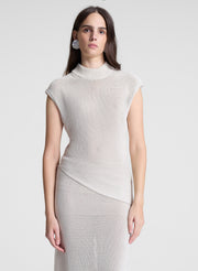 woman wearing cream asymmetric knit top and matching midi skirt