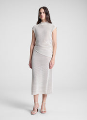 woman wearing cream asymmetric knit top and matching midi skirt