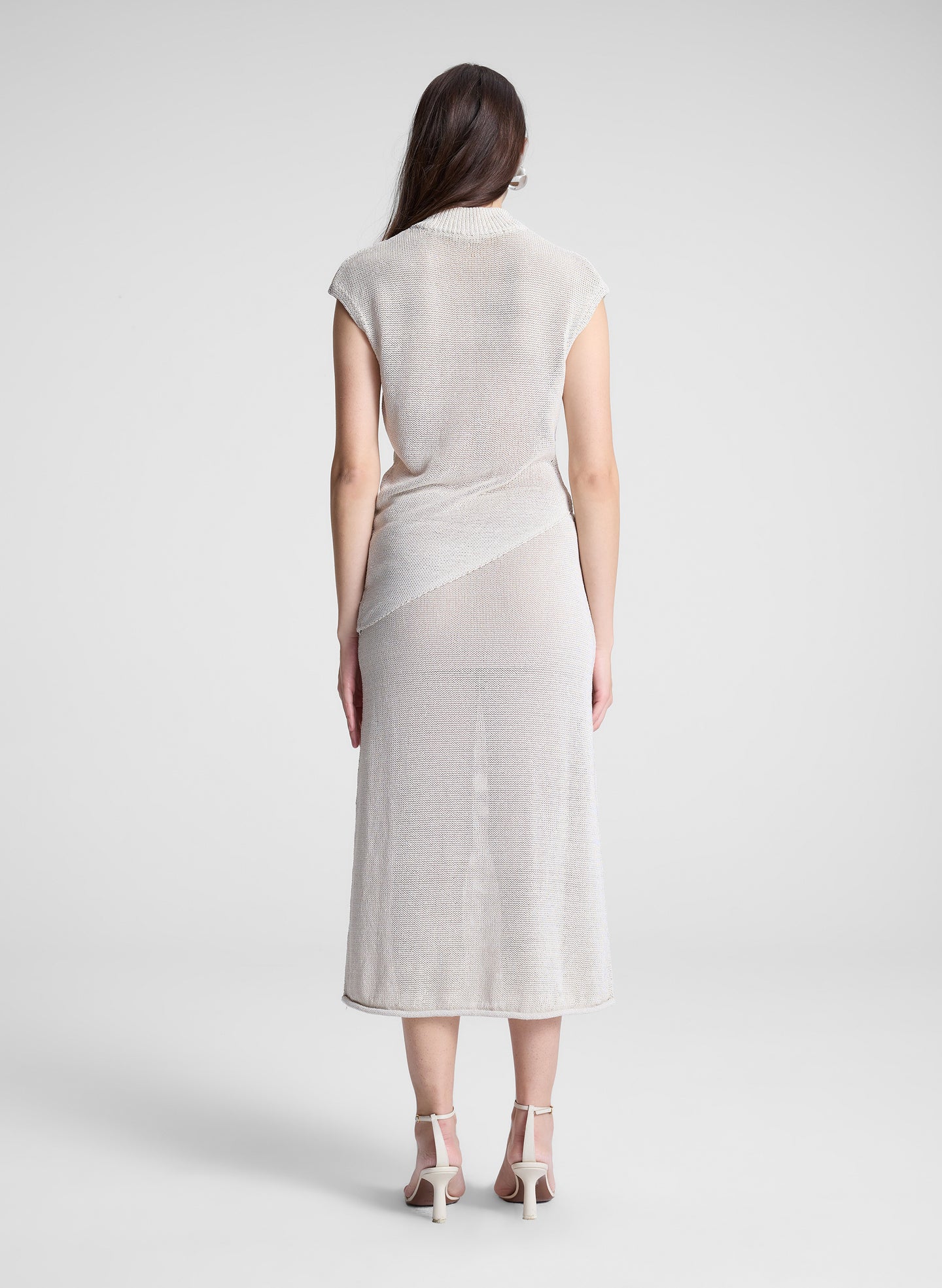 woman wearing cream asymmetric knit top and matching midi skirt