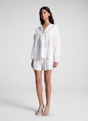 woman wearing white lace blouse and white shorts