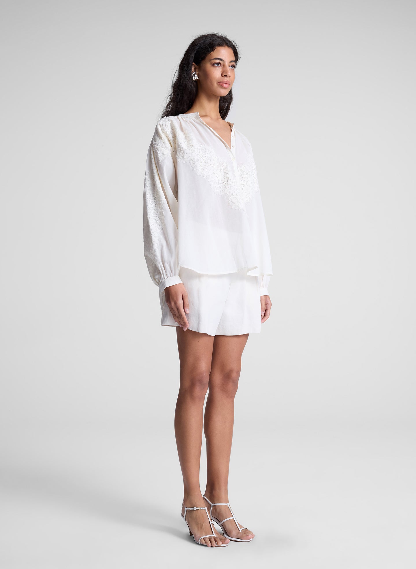 woman wearing white lace blouse and white shorts