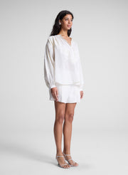 woman wearing white lace blouse and white shorts