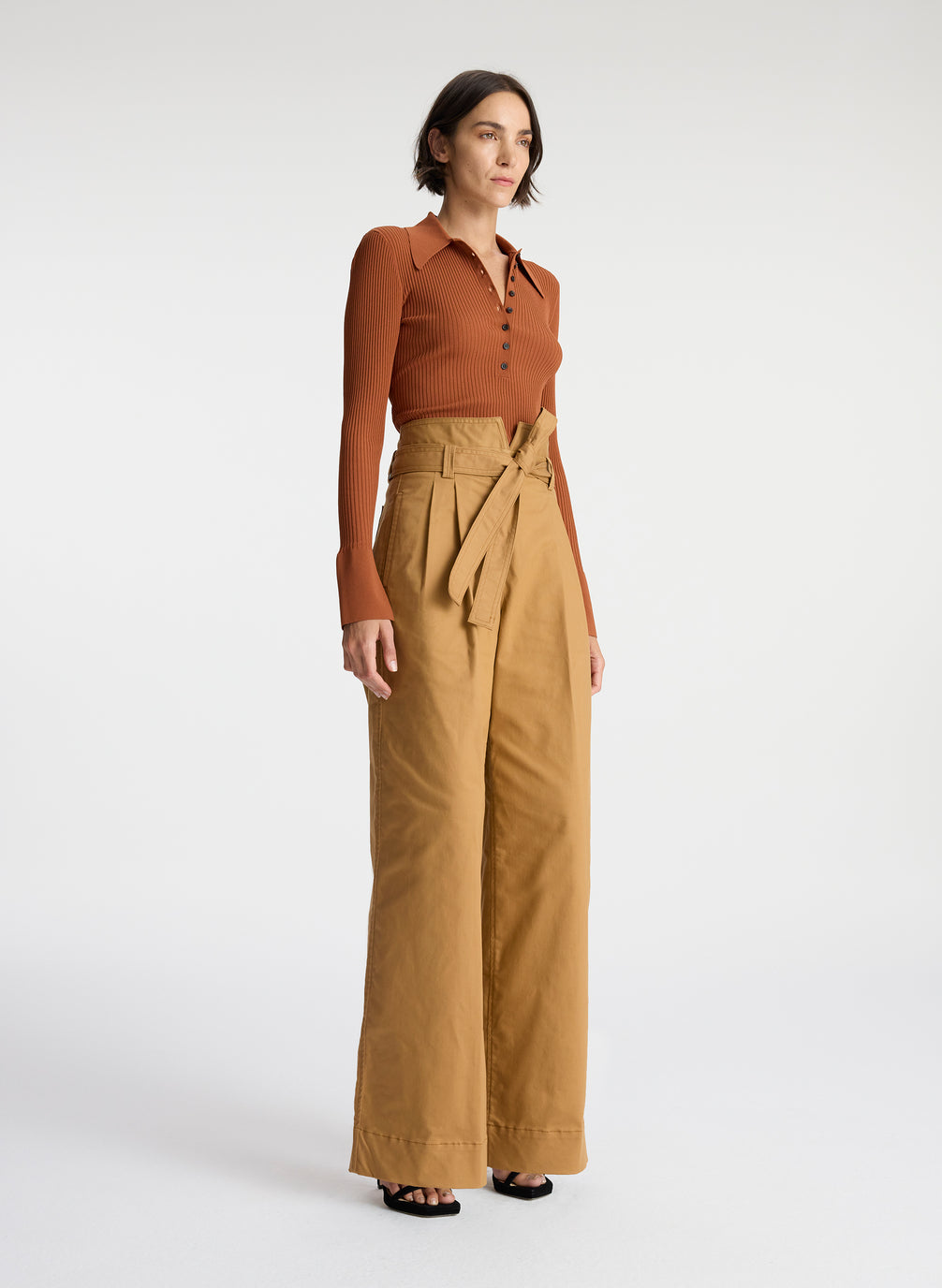 side view of woman wearing brown button up sweater with tan wide leg pants